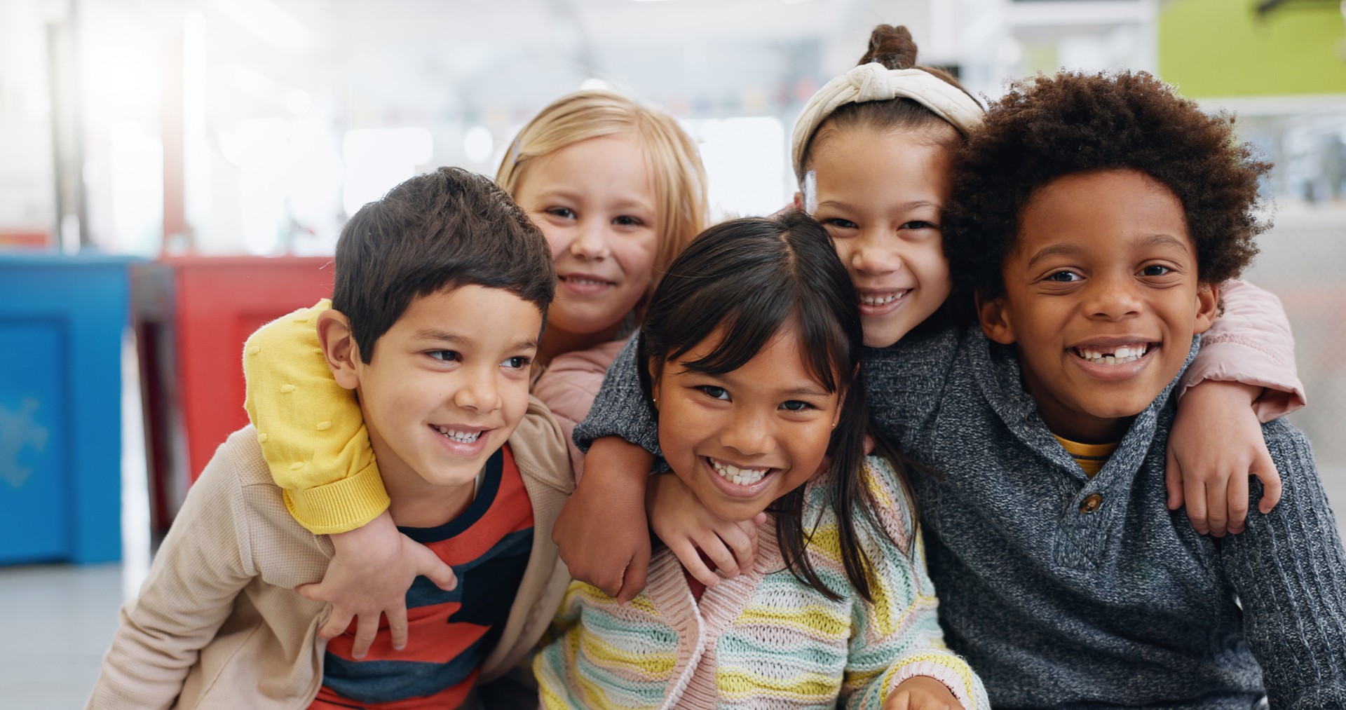 Portrait, group and kids with smile at school for education, learning and knowledge with hug. Student, children or face with happiness in classroom for study, scholarship or childhood development